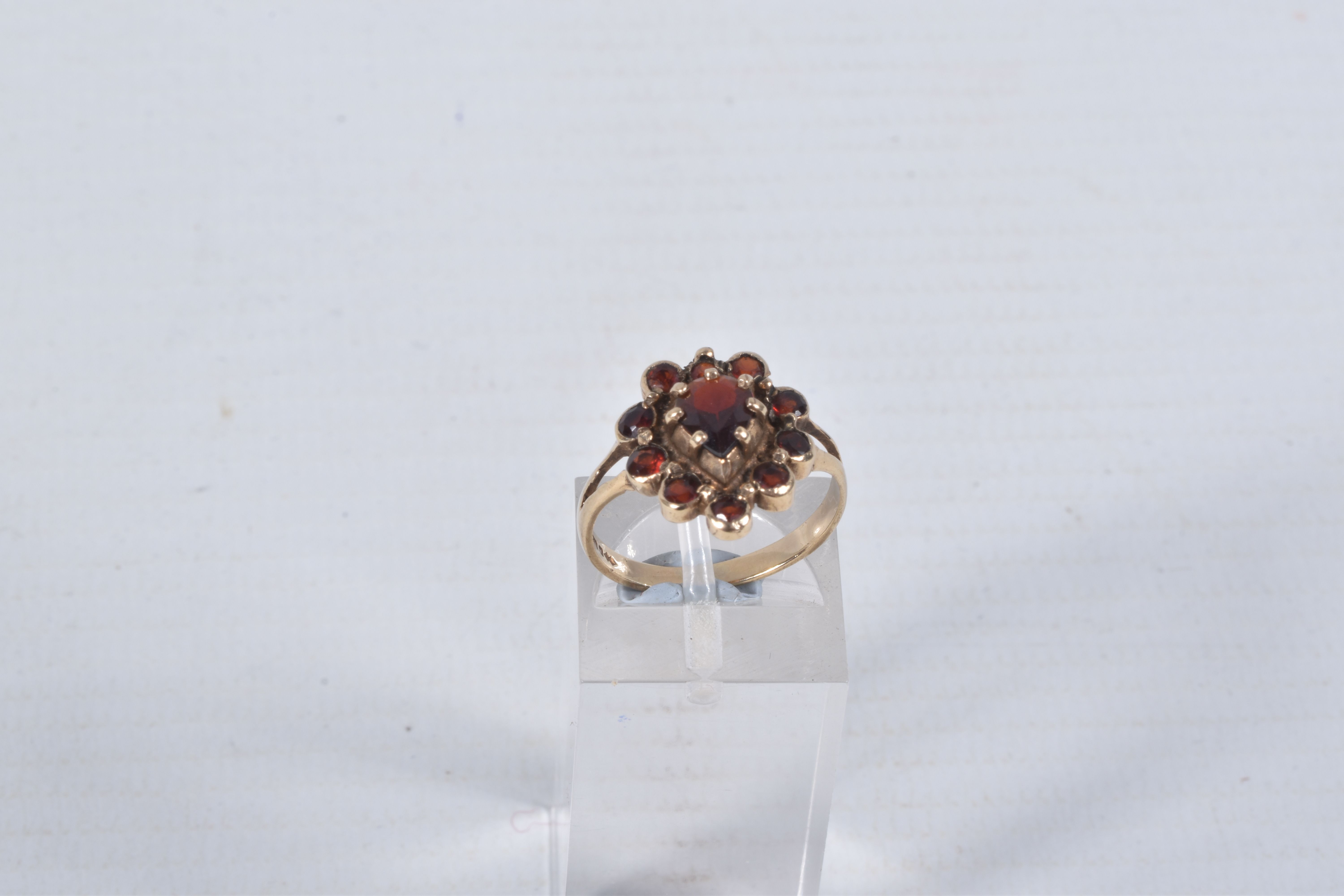 A 9CT GOLD GARNET CLUSTER RING, designed as a central pear shape garnet within a circular cut garnet