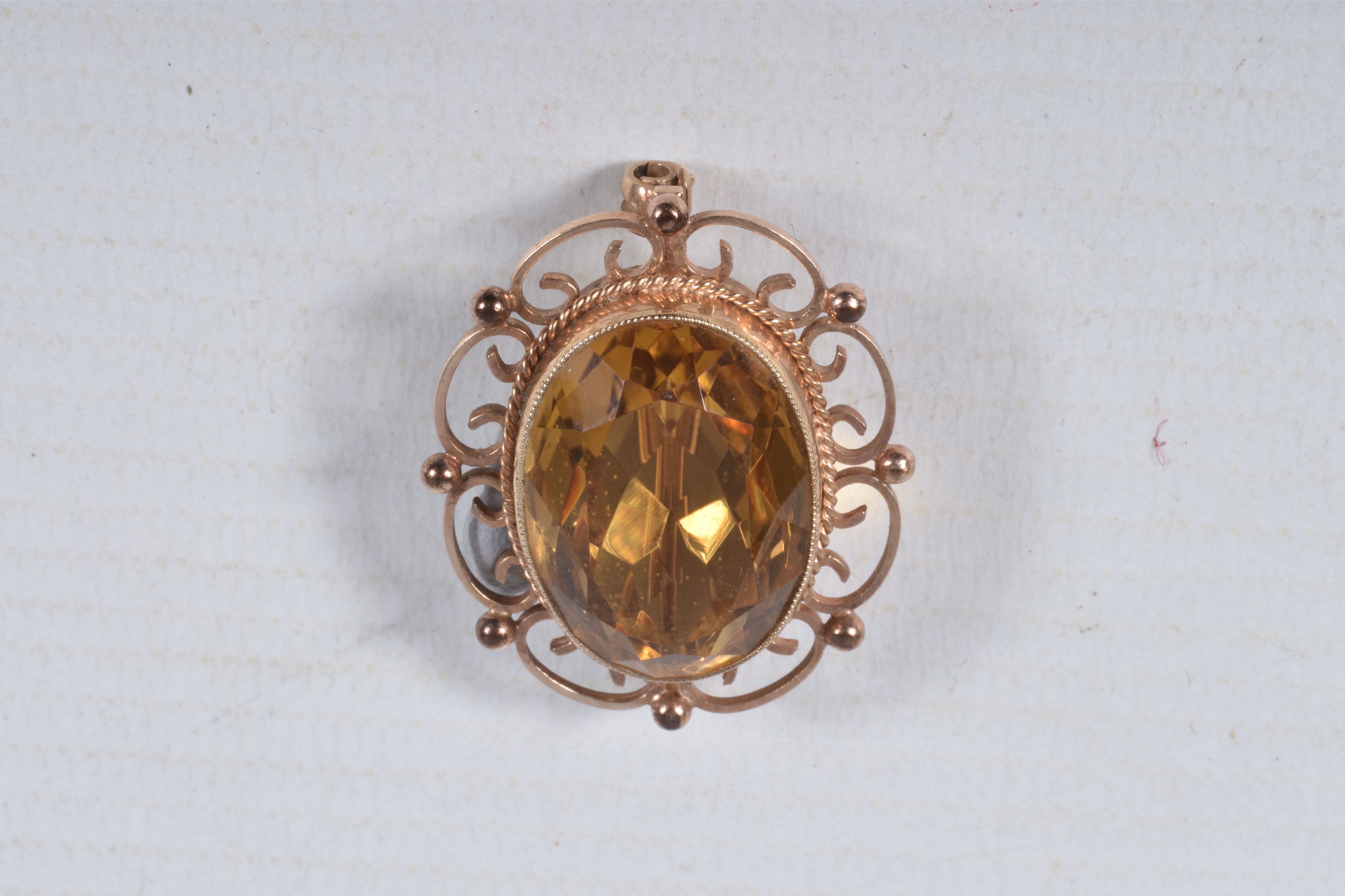 A 9CT GOLD CITRINE BROOCH, of an oval form, set with a large oval cut citrine, in a milgrain