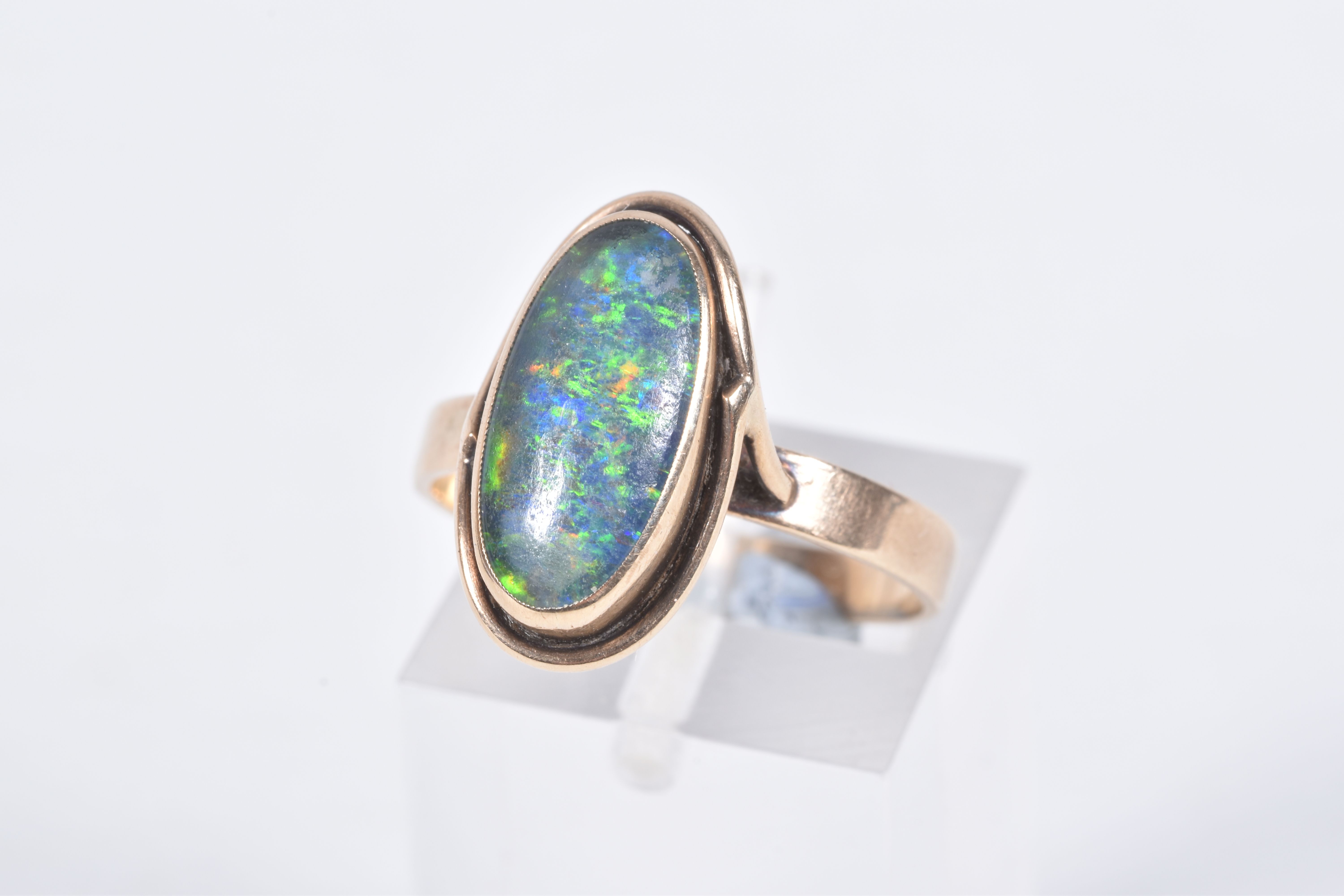 A YELLOW METAL OPAL TRIPLET RING, of an oval design, collet set opal triplet, to a scroll surround