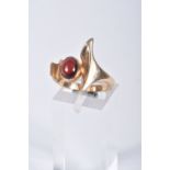 A 9CT GOLD GARNET DRESS RING, abstract design set with an oval garnet cabochon, collet set between