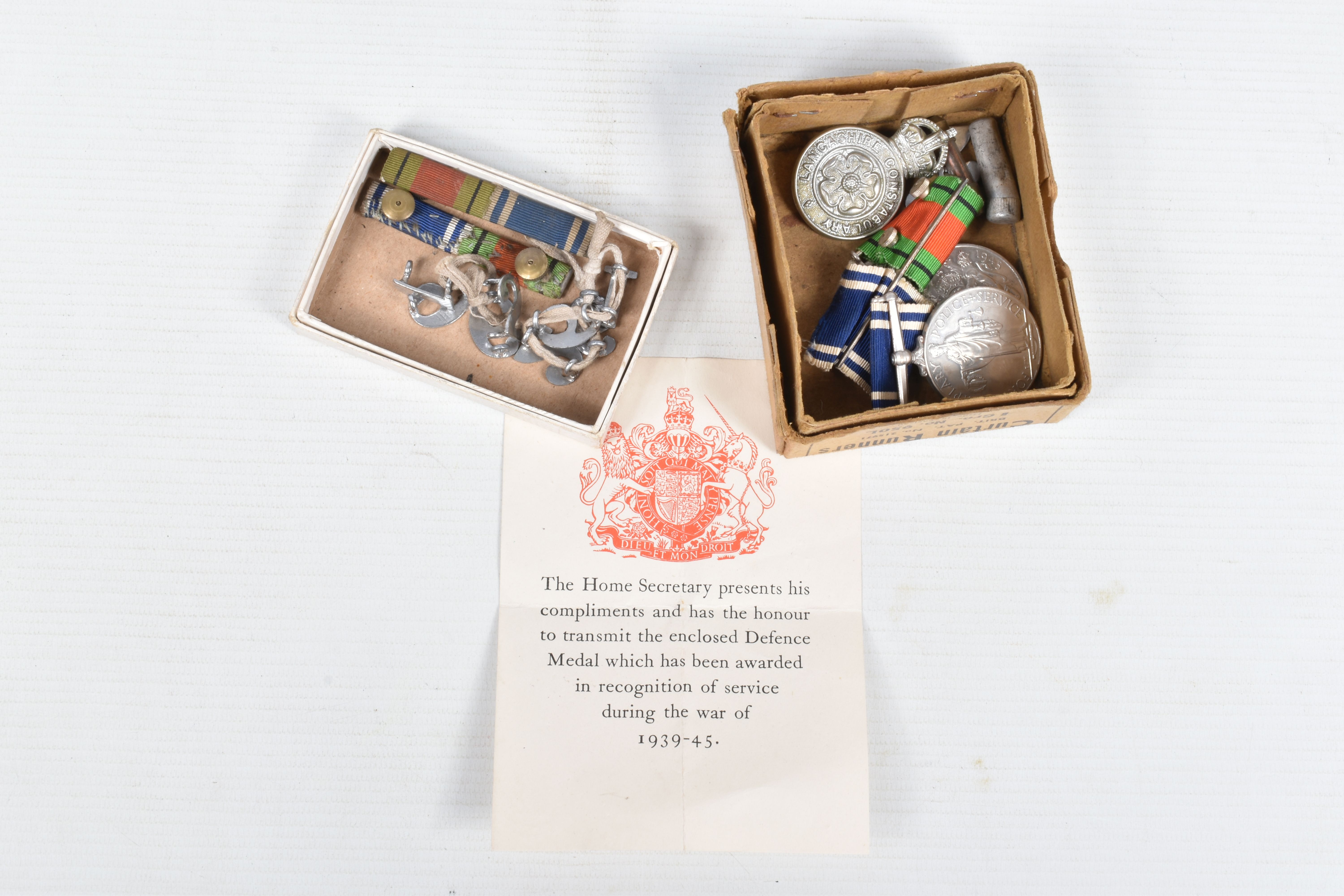 A POLICE LONG SERVICE MEDAL AND WWII DEFENCE MEDAL, police cap badge and epaulette numbers, the