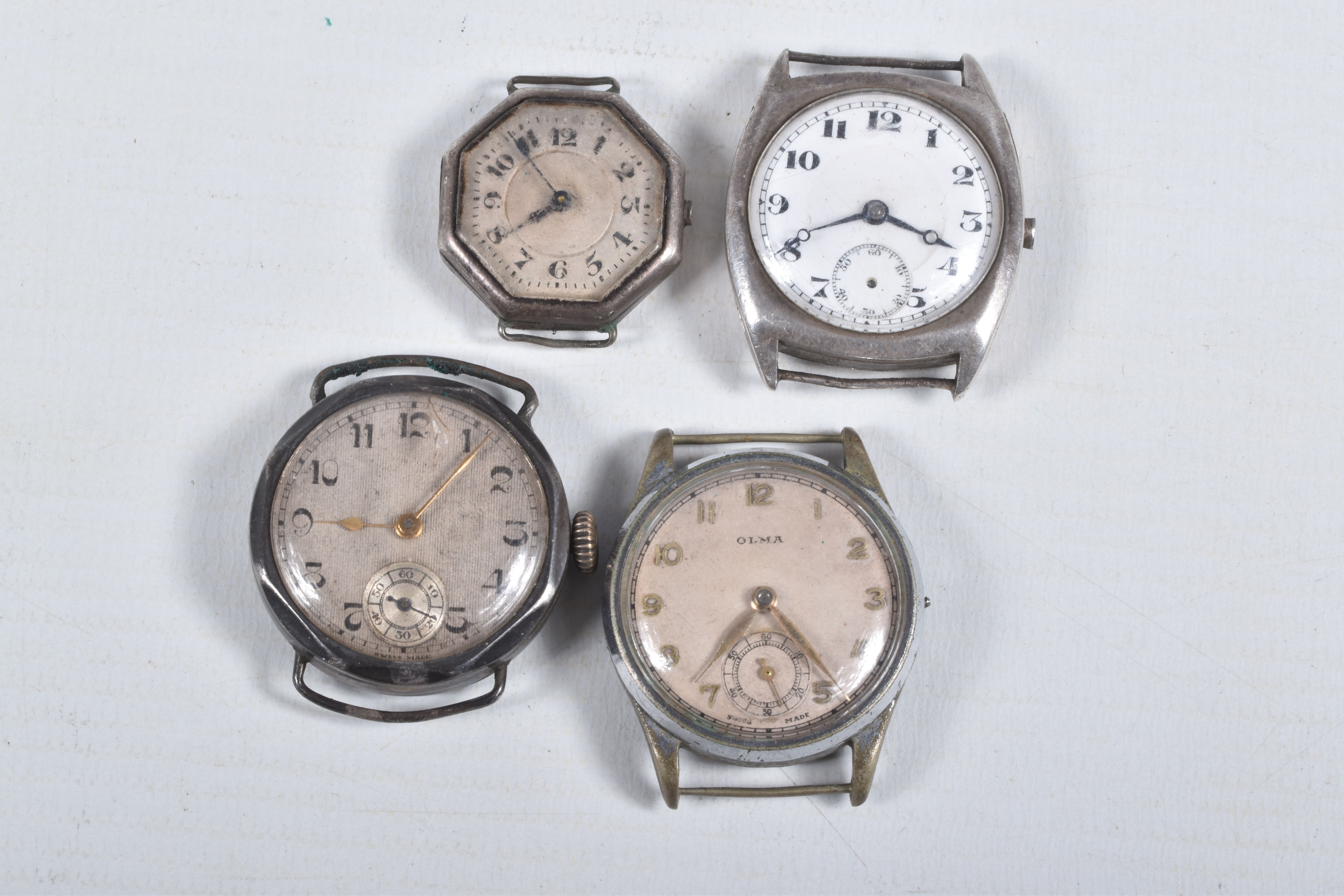 FOUR MID 20TH CENTURY WATCH HEADS, to include a white metal 'Olma' watch head, missing crown,