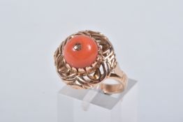 A YELLOW METAL CORAL RING, set with a raised coral cabochon with pin to the centre, in a claw