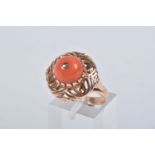 A YELLOW METAL CORAL RING, set with a raised coral cabochon with pin to the centre, in a claw