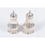 A PAIR OF EDWARDIAN SILVER PEPPERETTES, baluster form, on oval bases with pointed finial covers,