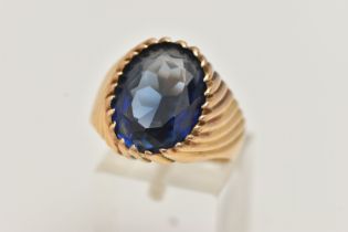 A GEM SET SIGNET RING, designed with an oval sapphire in a tapered ring mount with banded detail,