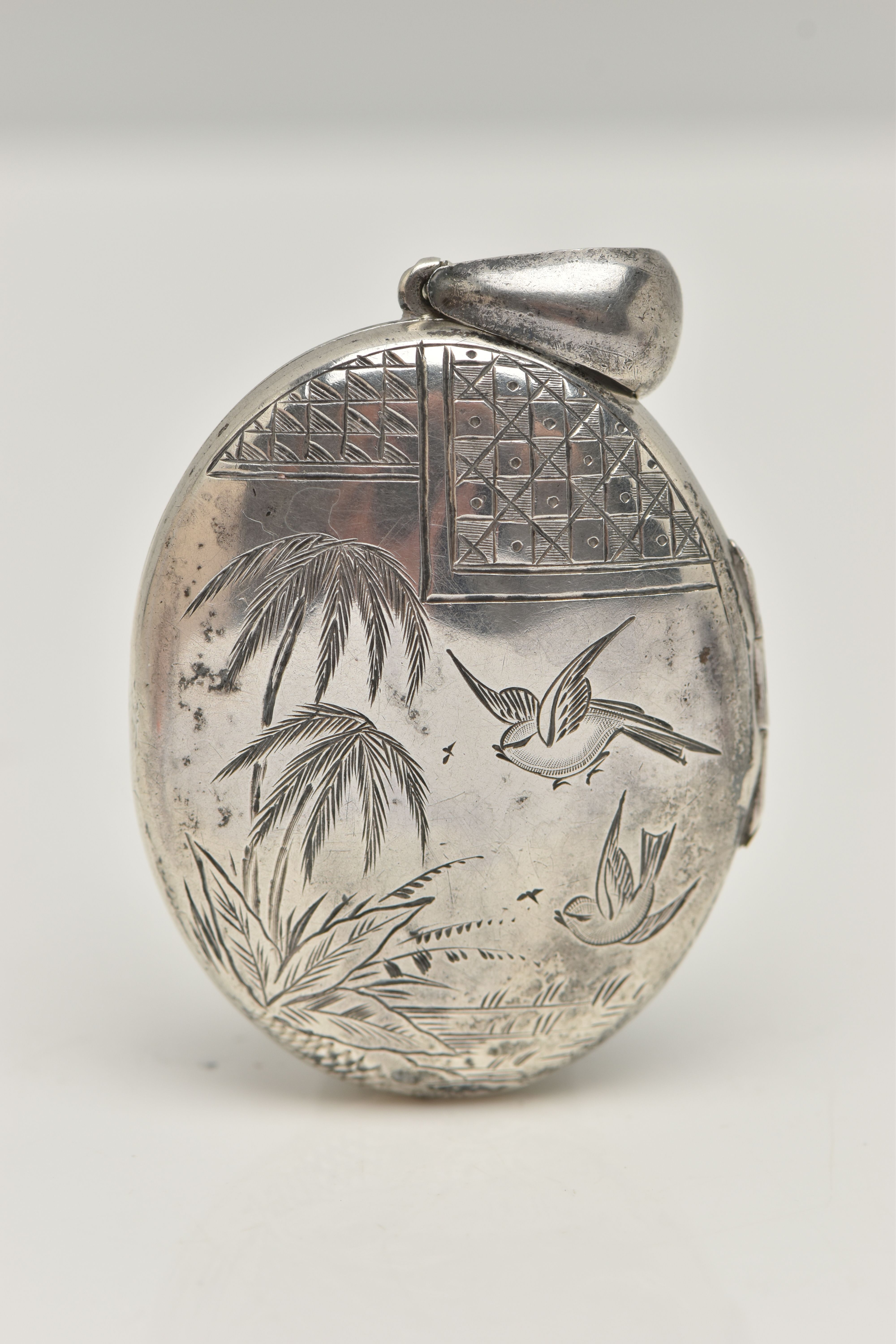 A VICTORIAN SILVER LOCKET, oval form locket with etch detail of palm trees and swallows, fitted with
