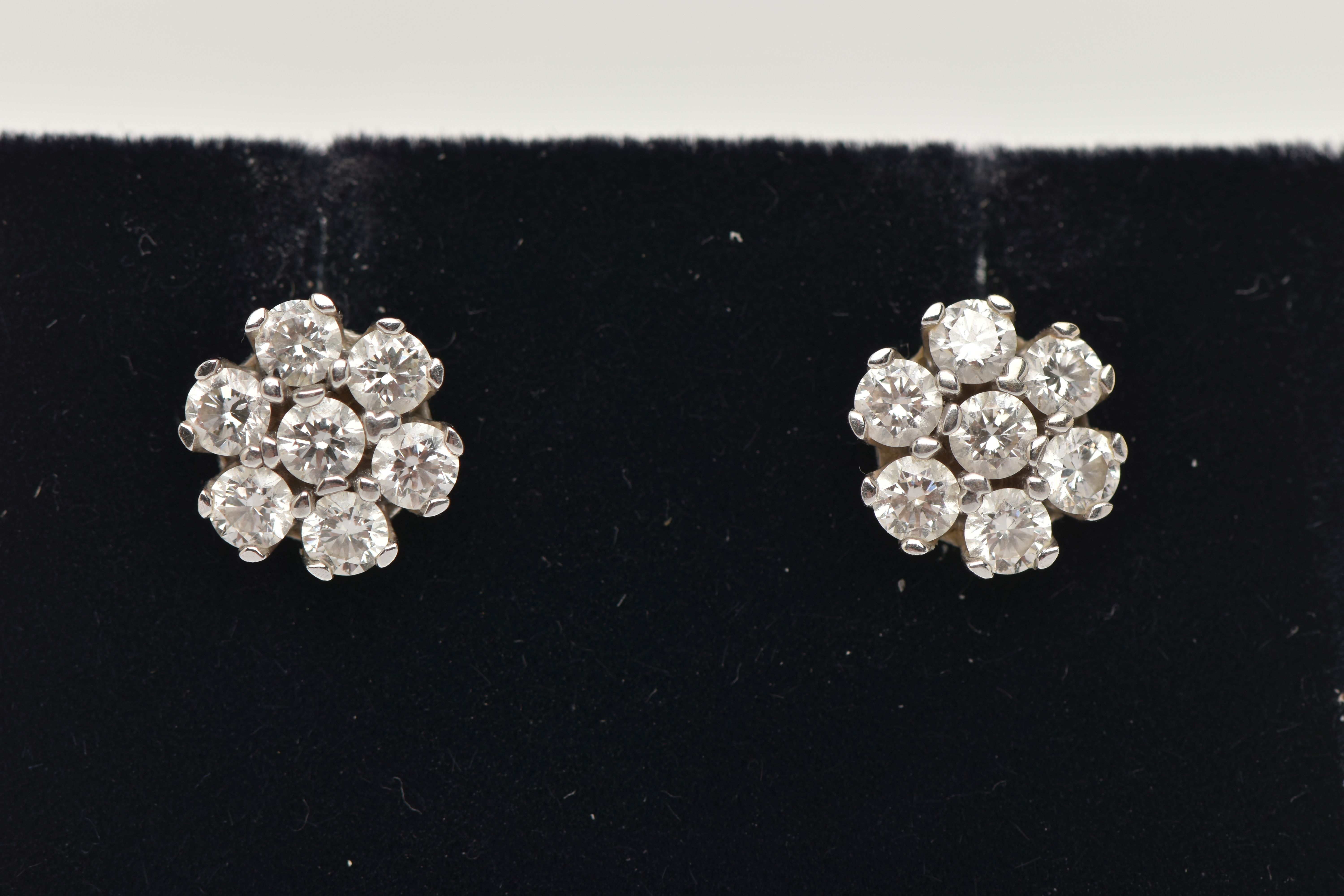 A PAIR OF WHITE METAL DIAMOND CLUSTER EARRINGS, each of a flower shape, set with seven round