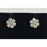 A PAIR OF WHITE METAL DIAMOND CLUSTER EARRINGS, each of a flower shape, set with seven round
