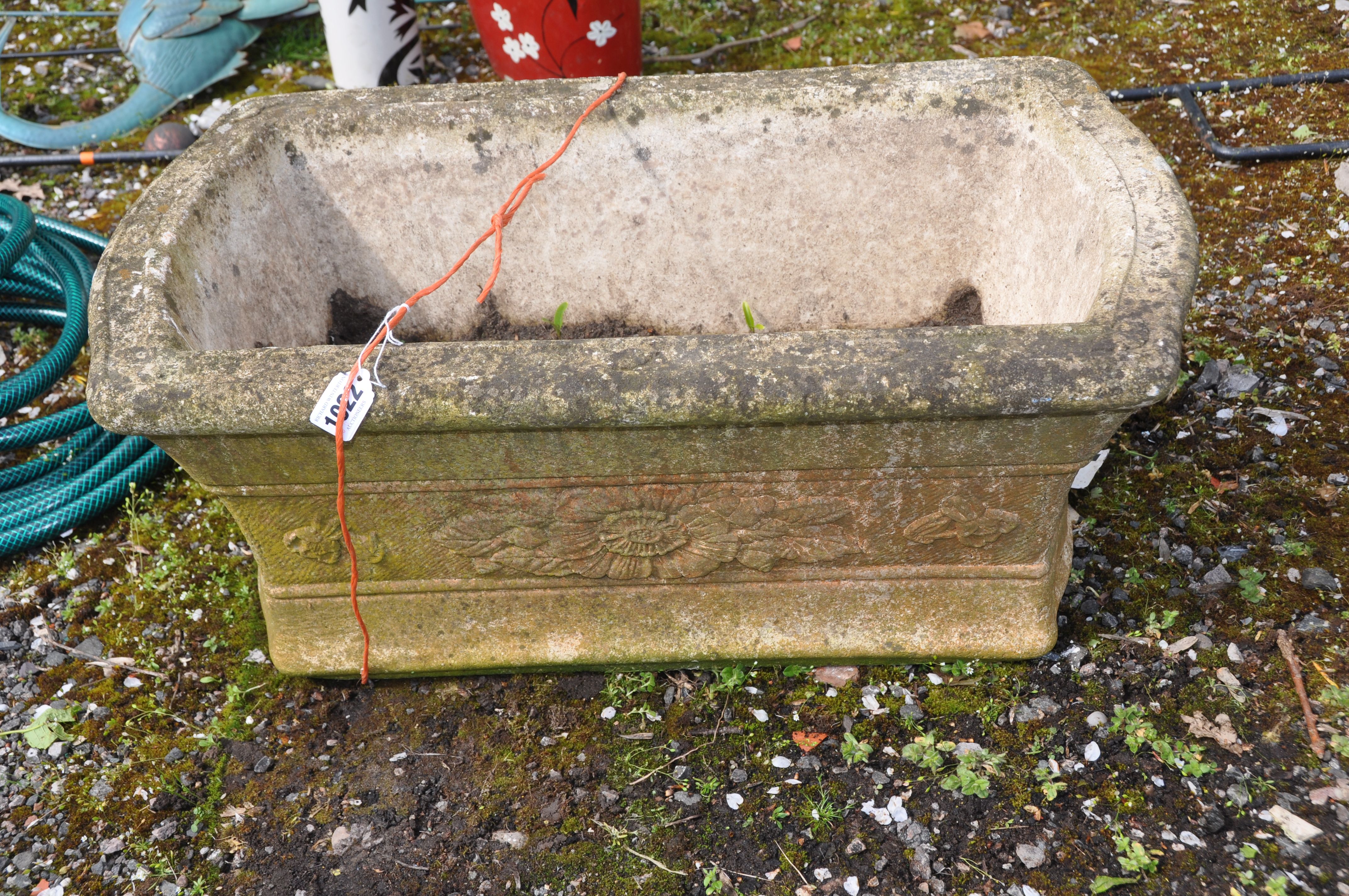 A WEATHERED COMPOSITE GARDEN PLANTER rectangular with flared sides and floral detail length 63cm