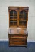 A 20TH CENTURY OAK BUREAU BOOKCASE, fitted with double glazed doors, that are enclosing two shelves,