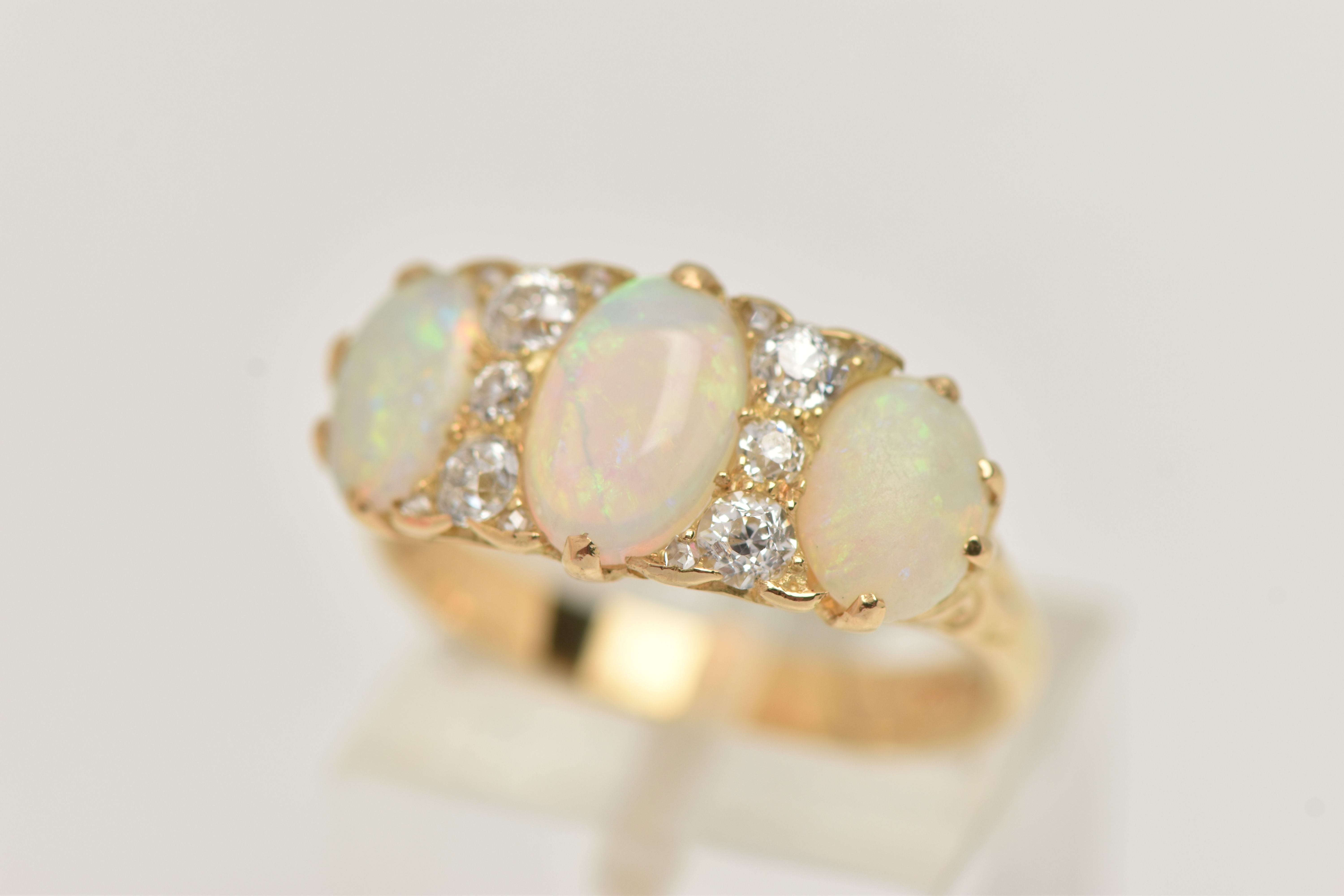 AN EARLY 20TH CENTURY OPAL AND DIAMOND RING, set with graduating oval opal cabochons, measuring from