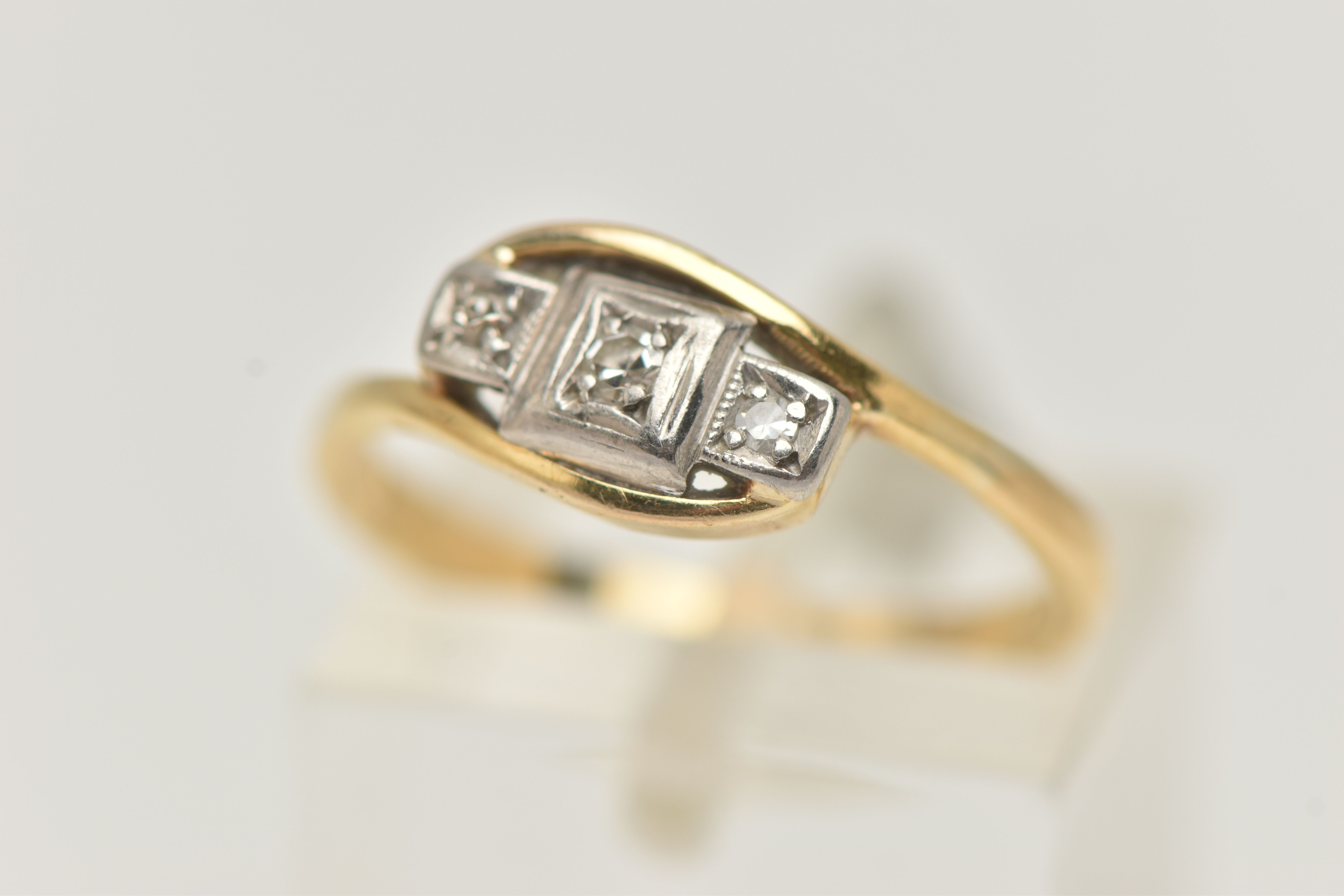 A THREE STONE DIAMOND RING, three single cut diamonds, prong set in white metal, leading on to a