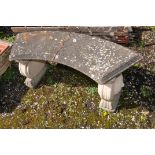 A WEATHERED COMPOSITE CURVED GARDEN BENCH with lion head motifs to each base 123cm long (condition