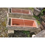 A PAIR OF WEATHERED COMPOSITE RECTANGULAR BRICK EFFECT PLANTERS with matching bases and plastic