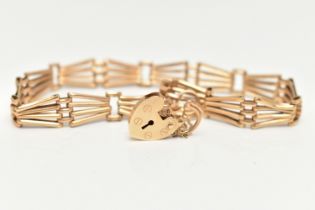 A 9CT YELLOW GOLD BRACELET WITH PADLOCK CLASP, the plain polished abstract design four row gate