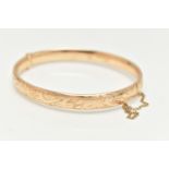 A 9CT GOLD HINGED BANGLE, with engraved scrolling acanthus decoration throughout to the hidden
