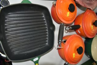 LE CREUSET KITCHEN WARE IN GREEN AND ORANGE, comprising a set of three orange saucepans with lids in