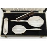 A CASED FOUR PIECE SILVER VANITY SET, to include a hair brush, hand held mirror, clothes brush and a