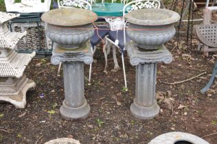 A PAIR OF CAMPAGNA GARDEN URNS, possibly basalt or slate like material, with both sat on similar