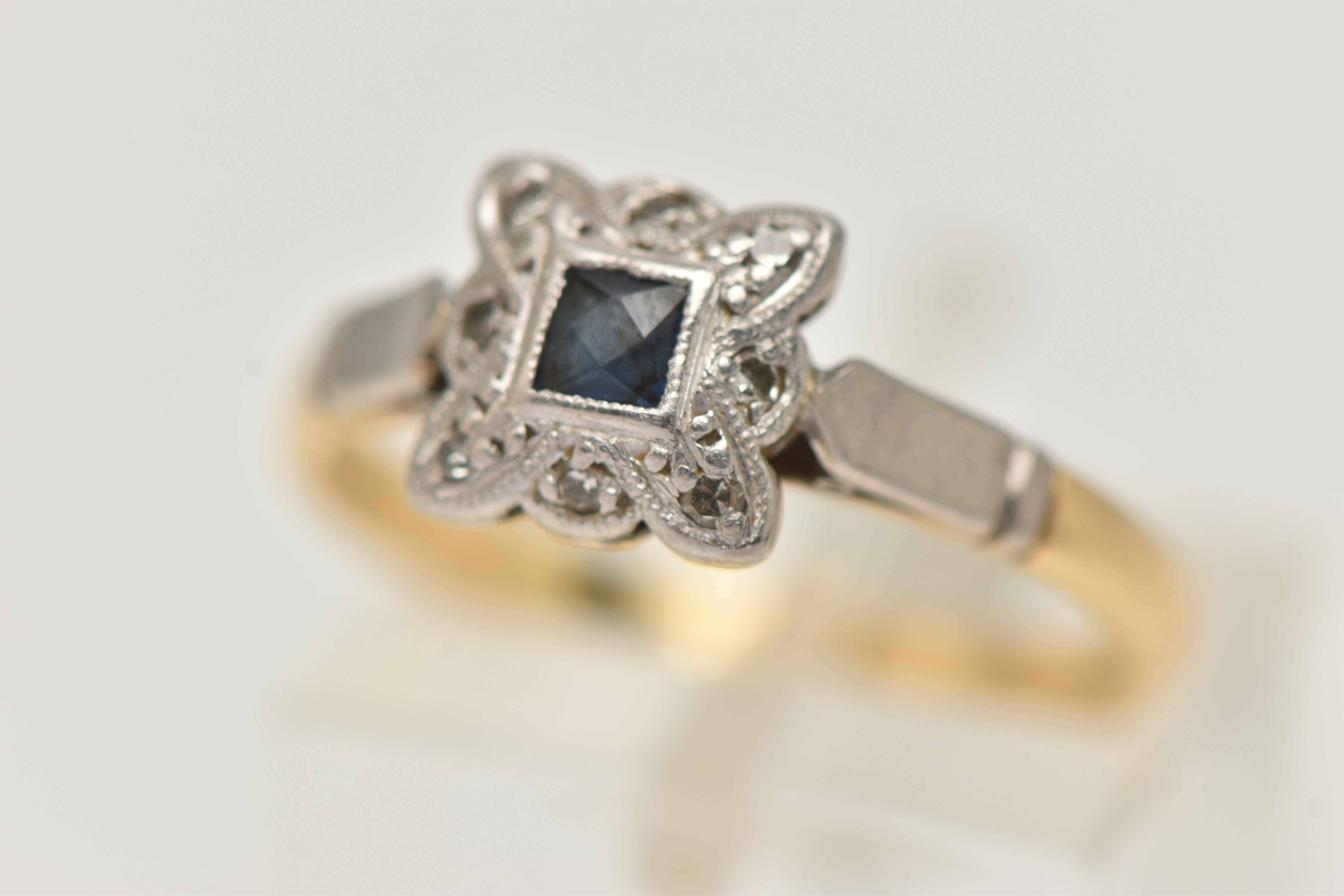A YELLOW AND WHITE METAL SAPPHIRE AND DIAMOND RING, set centrally with a deep blue square cut