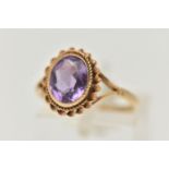 A 9CT GOLD AMETHYST RING, centering on an oval cut amethyst, collet set with a fine rope twist