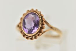 A 9CT GOLD AMETHYST RING, centering on an oval cut amethyst, collet set with a fine rope twist