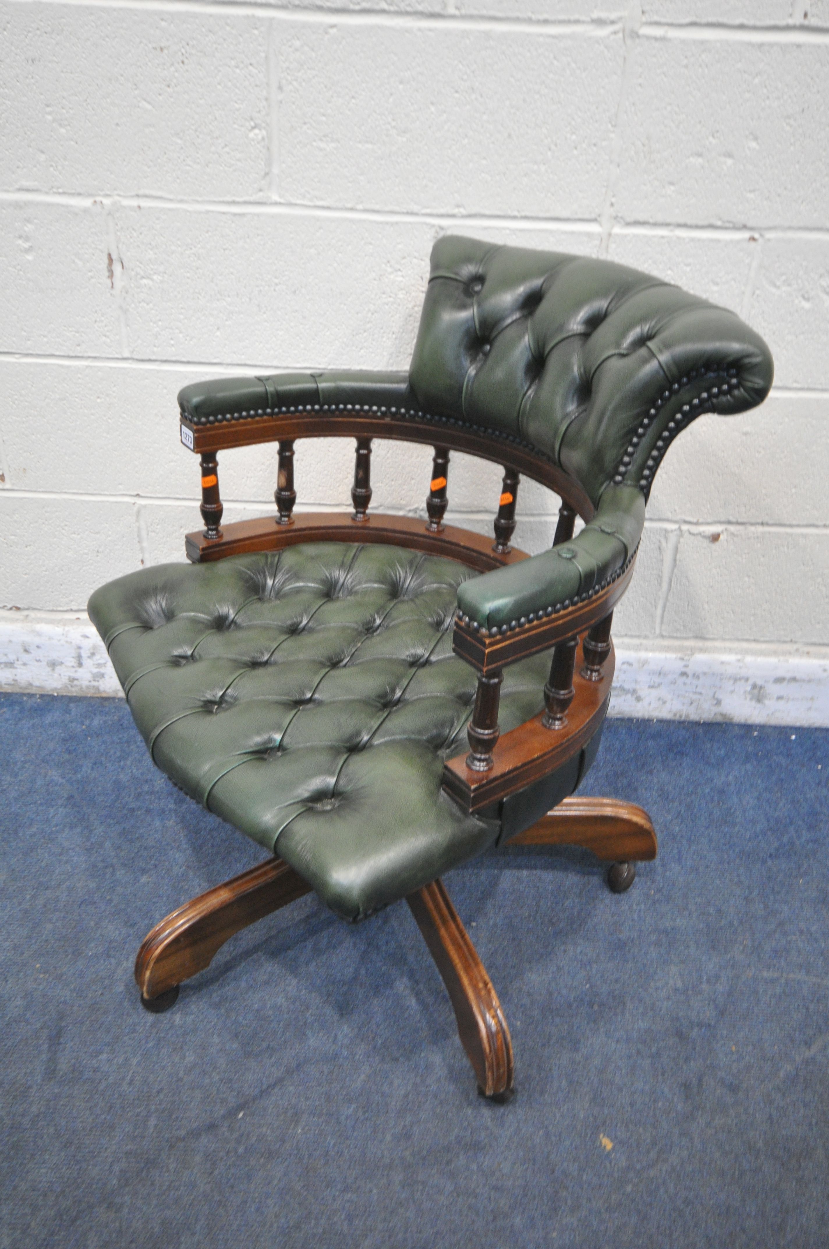 A 2OTH CENTURY MAHOGANY SWIVEL CAPTAINS CHAIR, with buttoned green leather upholstery, raised on