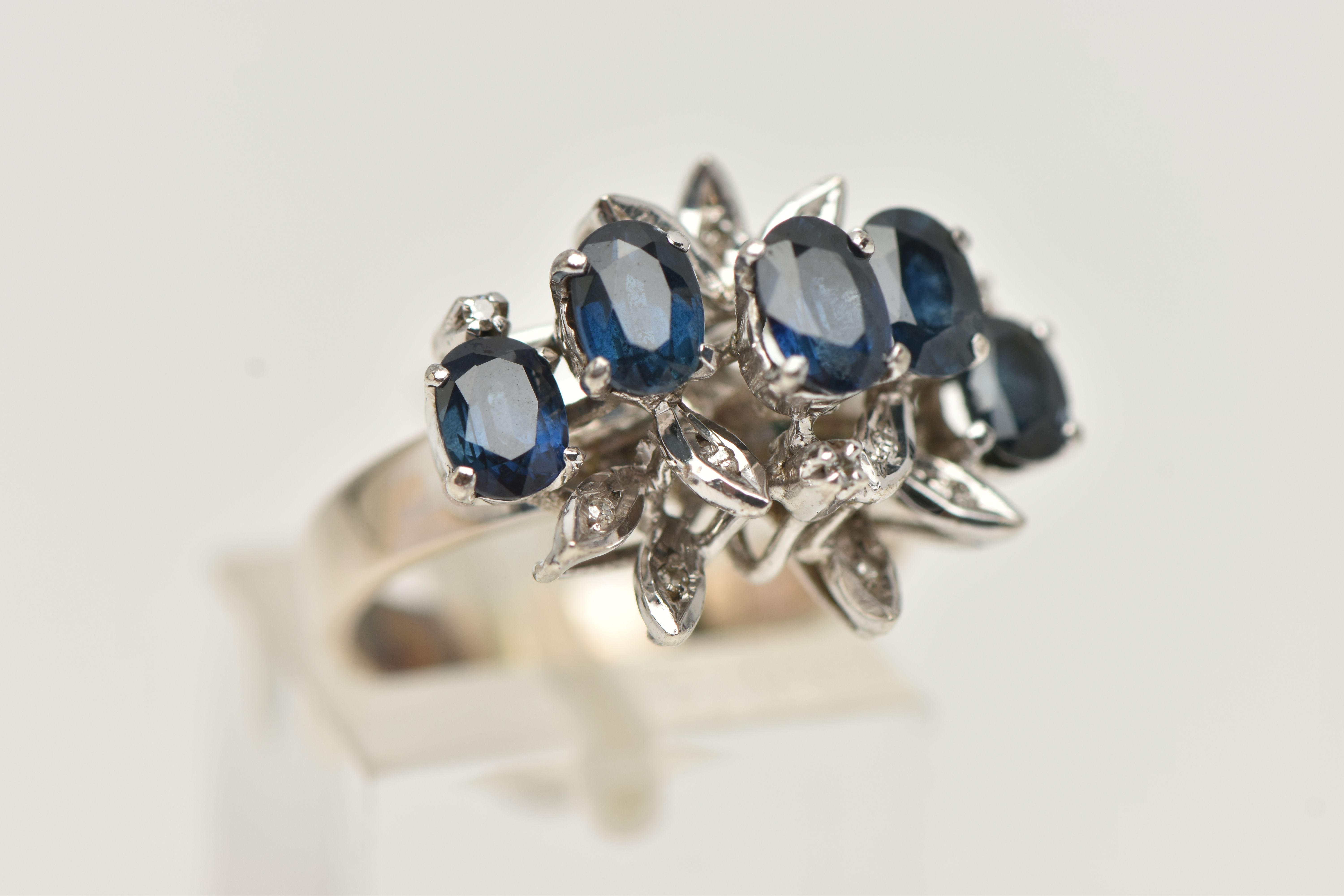 A WHITE METAL SAPPHIRE AND DIAMOND DRESS RING, set with five oval cut blue sapphires, single cut - Image 4 of 4