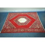 A RED GROUND SYNTHETIC SILK RUG, with central medallion, foliate designs and multi-strap border,