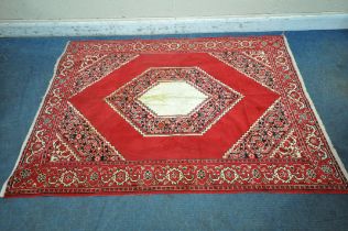 A RED GROUND SYNTHETIC SILK RUG, with central medallion, foliate designs and multi-strap border,