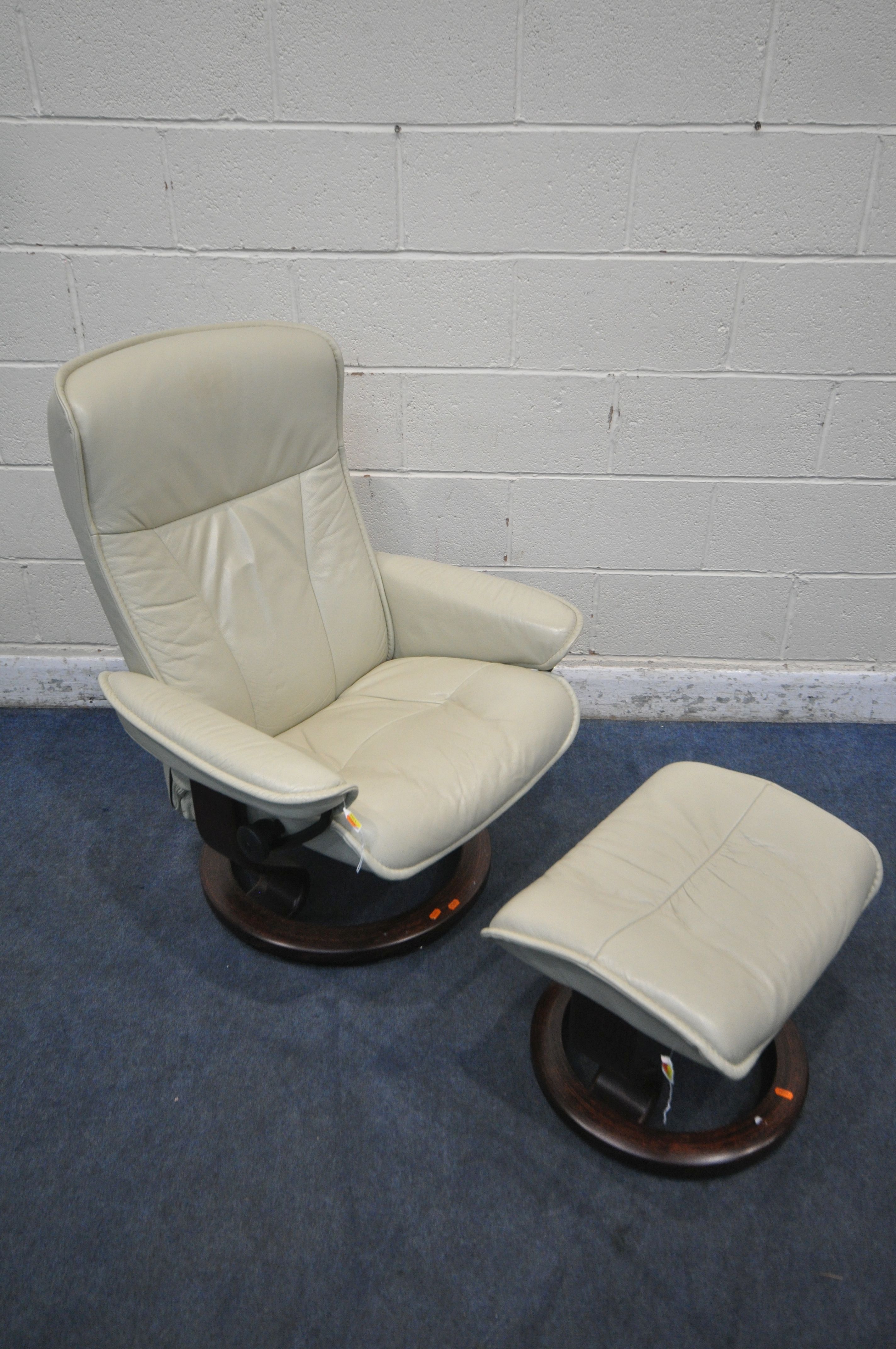 AN EKORNES STRESSLESS CREAM LEATHER RECLINING ARMCHAIR, with a matching footstool (condition report: