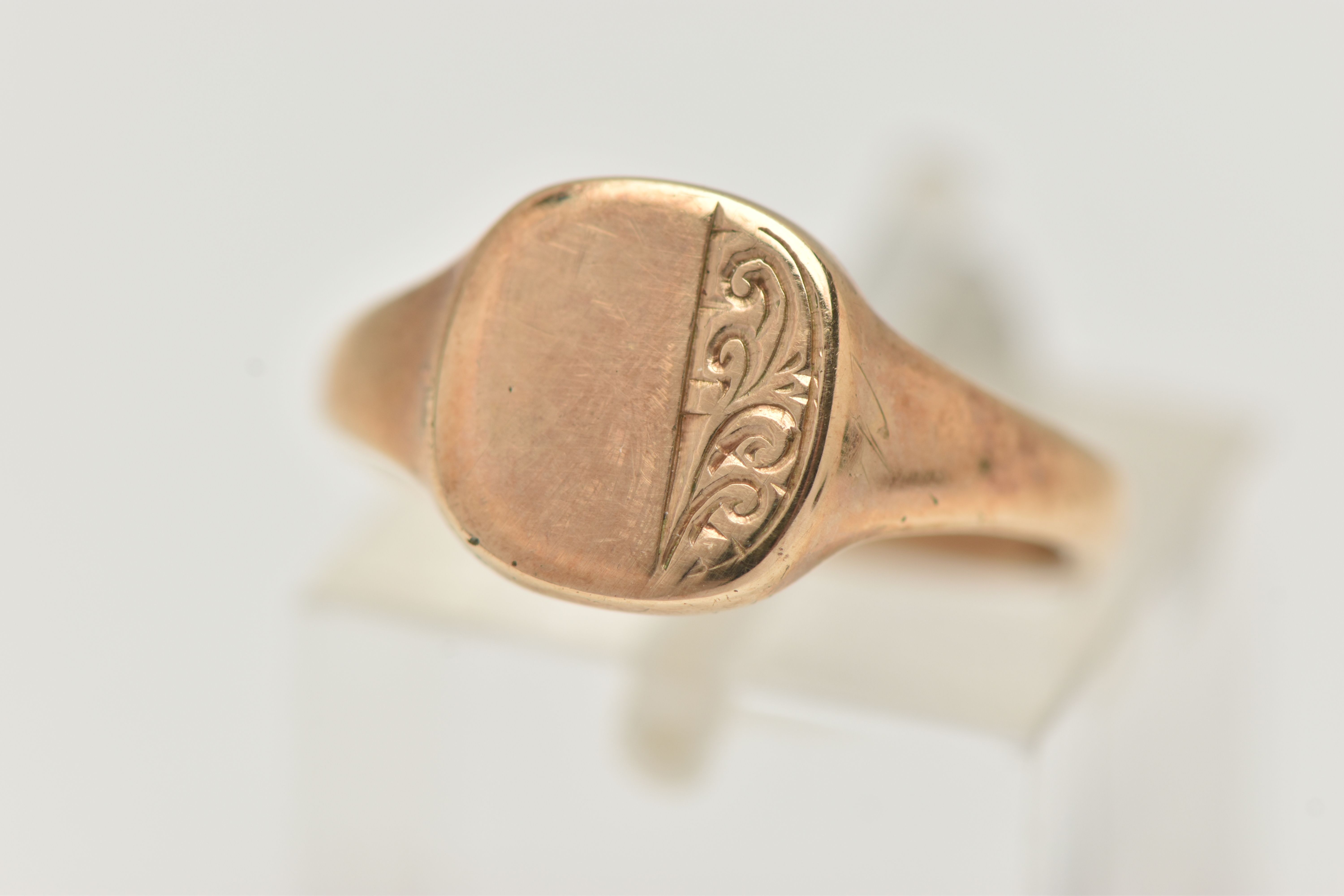 A 9CT GOLD SIGNET RING, rounded square form, with foliate pattern, tapering polished band,