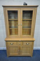 A MODERN LIGHT OAK BOOKCASE, the double glazed doors enclosing two glass shelves, atop a base fitted
