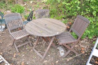A WOODEN SLATTED FOLDING GARDEN TABLE 89cm in diameter and three folding chairs (condition report: