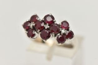 A WHITE METAL RUBY AND DIAMOND DRESS RING, set with ten circular cut rubies, each claw set, with