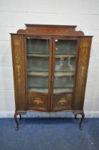 AN EDWARDIAN WALNUT AND INLAID SERPENTINE DISPLAY CABINET, the double glazed doors enclosing two