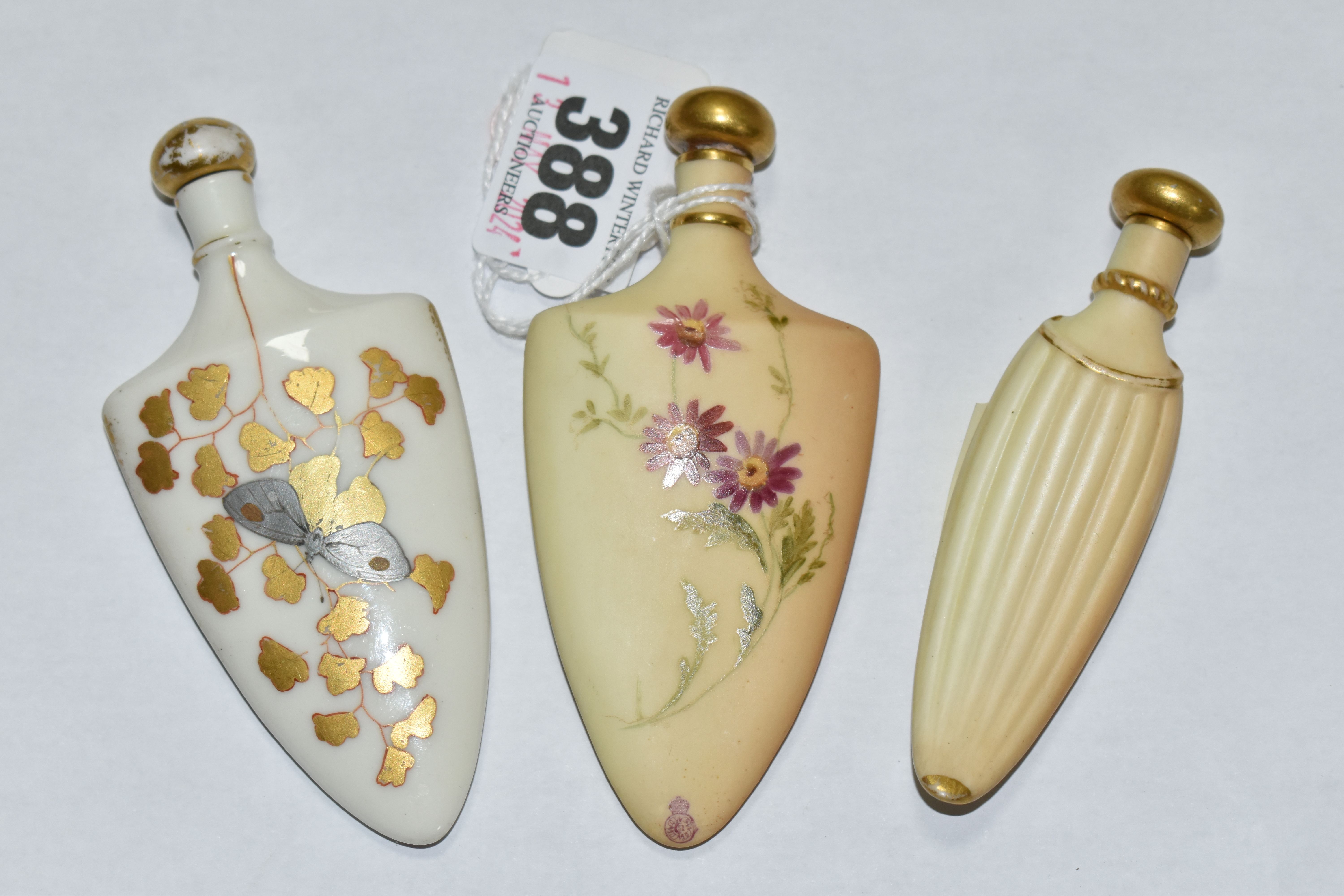 A GROUP OF THREE ROYAL WORCESTER PORCELAIN SCENT FLASKS, comprising a shield shaped bottle, hand