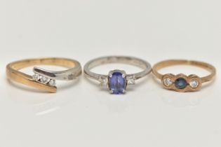 THREE 9CT GOLD GEM SET RINGS, the first a three stone diamond ring in a bi colour bypass mount,
