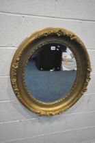 A 19TH CENTURY GILT WOOD OVAL WALL MIRROR, with floral carvings and a later bevelled edge plate,