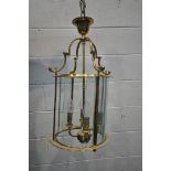 A 20TH CENTURY BRASS CYLINDRICAL HALL LANTERN, the glass panes encasing a four branch light fitting,