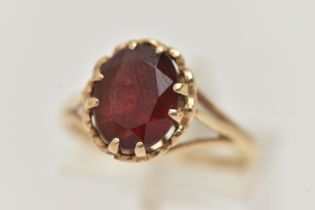 A 9CT GOLD GARNET SET RING, oval cut garnet in a double four claw setting, measuring approximately