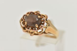 A YELLOW METAL SMOKY QUARTZ RING, set with an oval cut smoky quartz, in a four claw open work