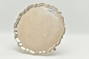 A GEORGE V SILVER SALVER, a circular form salver with a fluted border, raised on four scrolled feet,