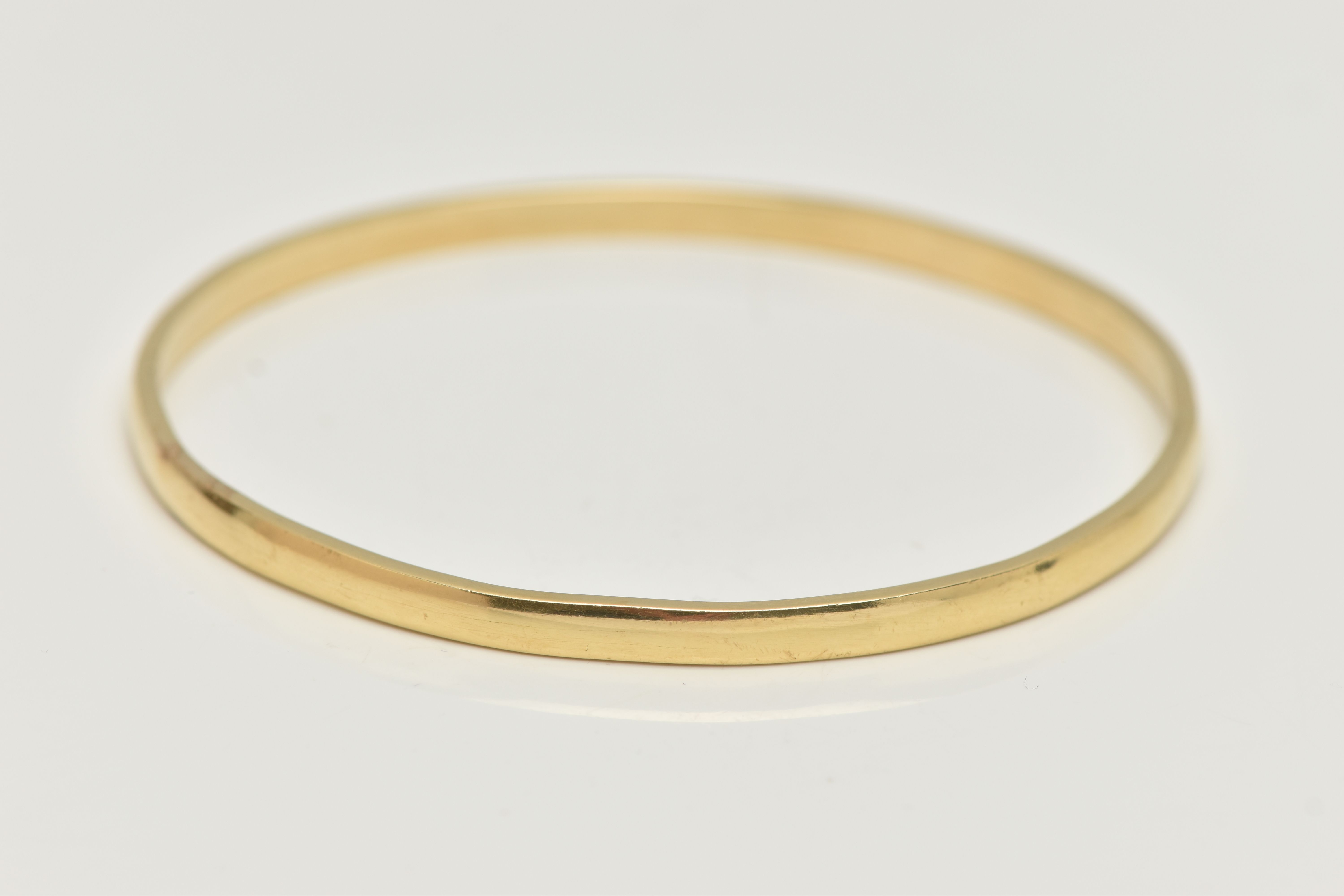 A YELLOW METAL SOLID BANGLE, circular form bangle, approximate width 3.9mm, approximate internal