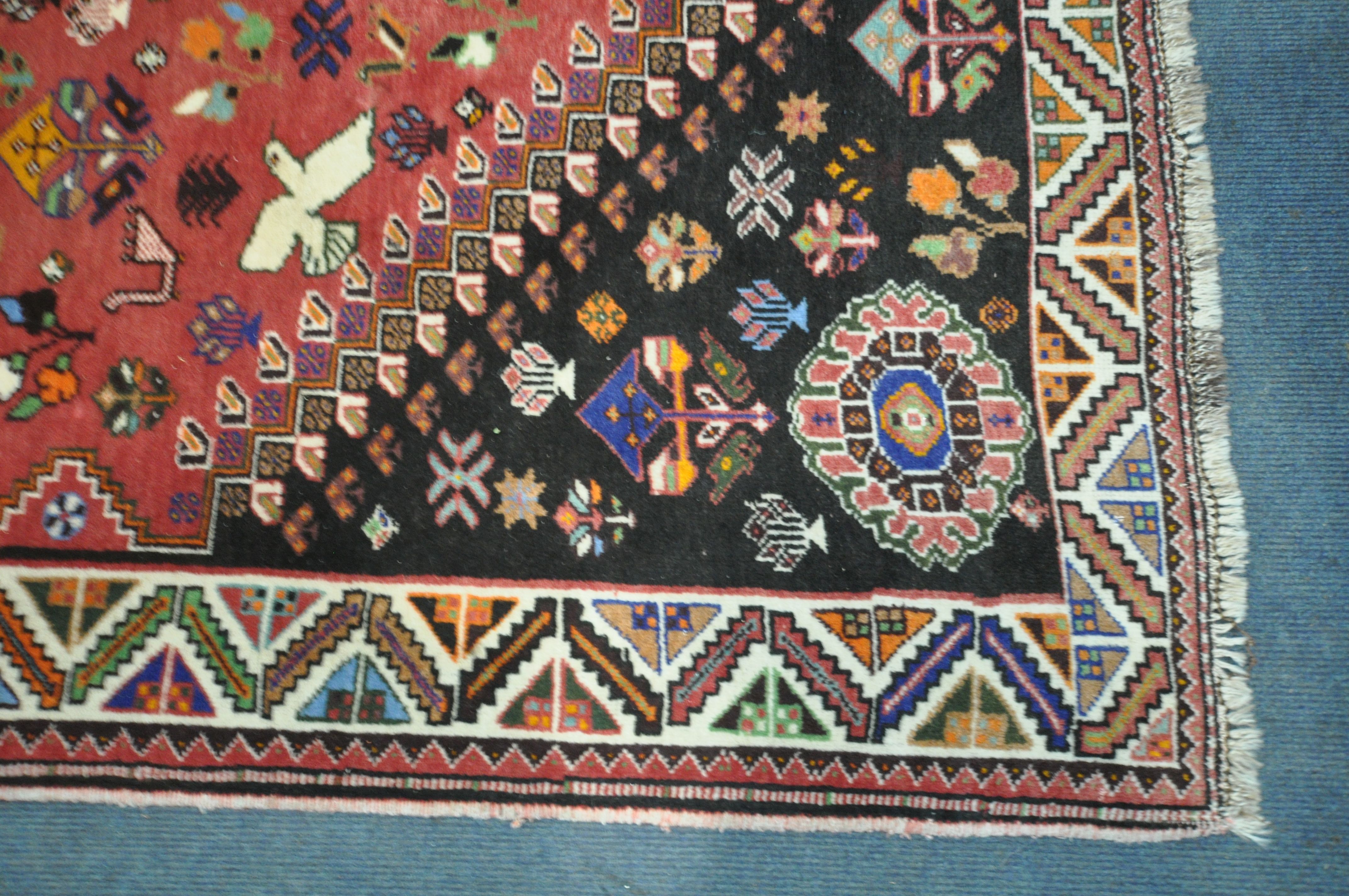 A WOOLLEN RED GROUND RUG, with a repeating pattern of birds, three central medallions, black - Image 5 of 6