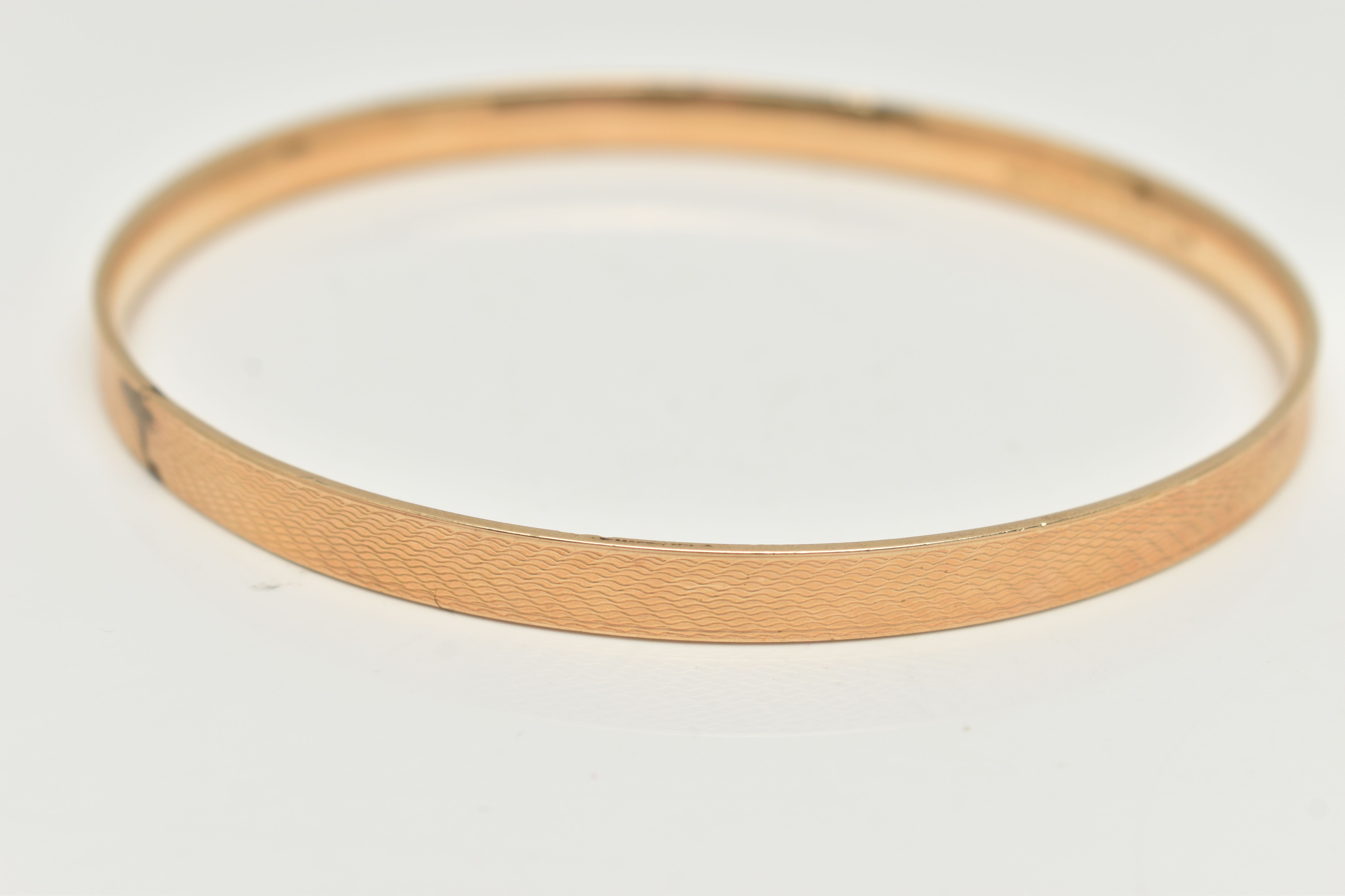 A 9CT GOLD METAL CORE BANGLE, engine turned pattern, stamped '9ct gold solid metal core', - Bild 2 aus 3