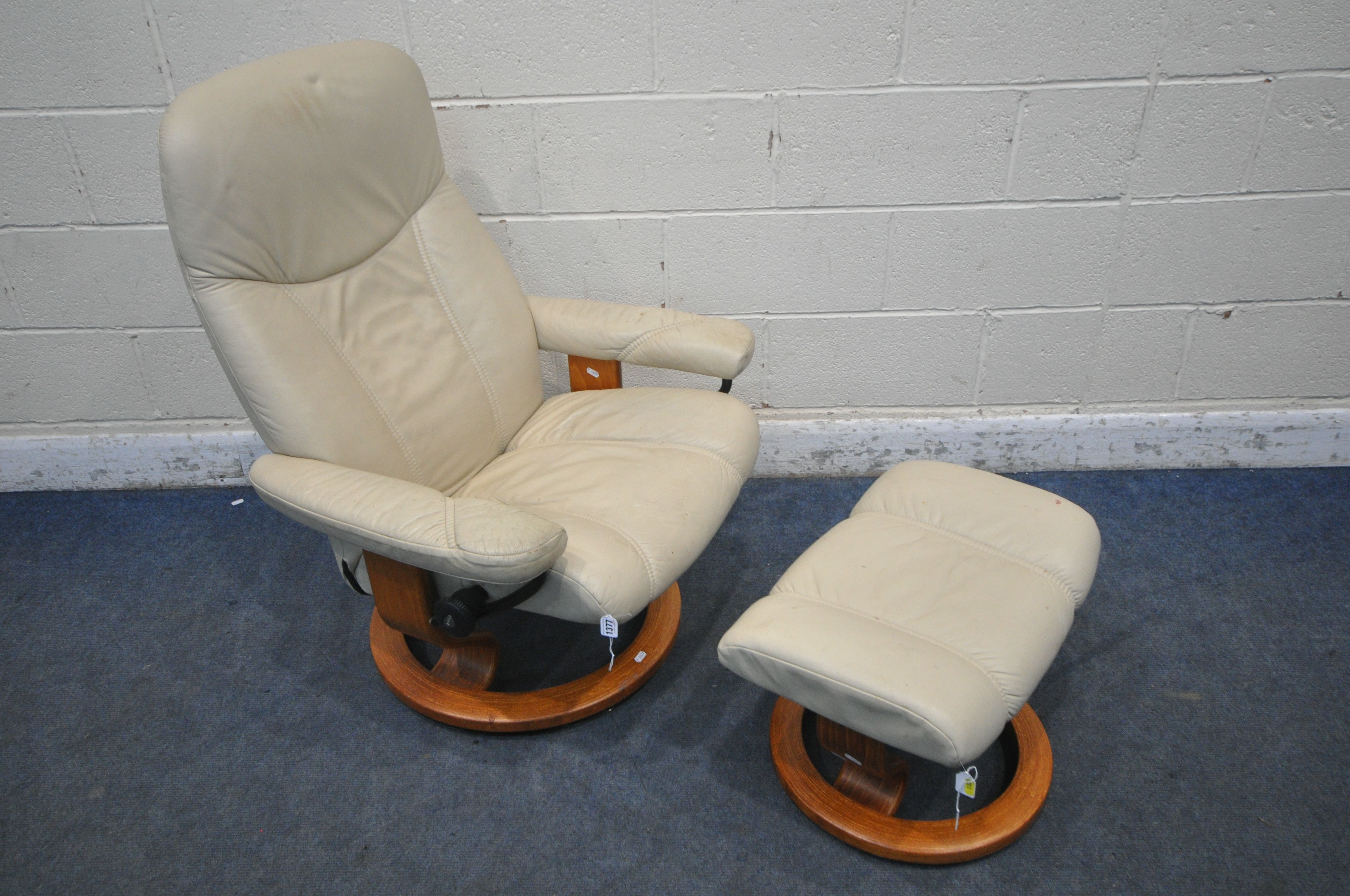 AN EKORNES STRESSLESS CREAM LEATHER SWIVEL RECLINING ARMCHAIR, along with a footstool (condition