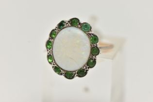 AN OPAL RING, the central opal cabochon within a green gem surround, assessed as green paste,