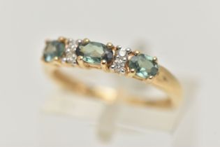 A 14CT GEMSTONE RING, designed as three oval cut green gems, assessed as topaz, interspaced by a